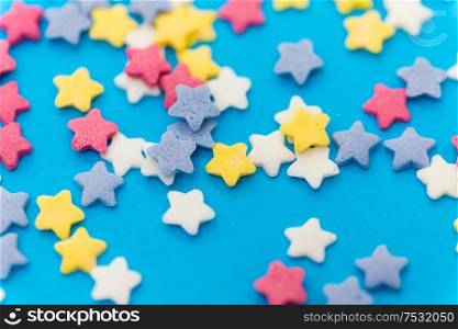 party, sweets and decoration concept - star shaped sugar sprinkles on blue background. star shaped pastry sprinkles on blue background
