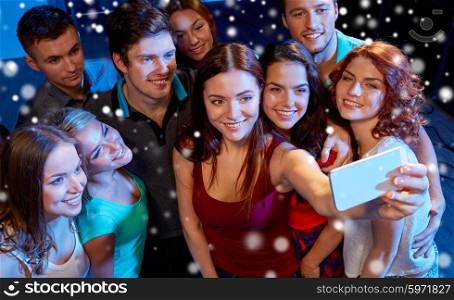 party, technology, nightlife and people concept - smiling friends with smartphone taking selfie in club and snow effect