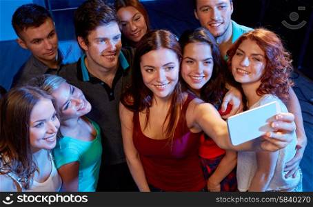 party, technology, nightlife and people concept - smiling friends with smartphone taking selfie in club