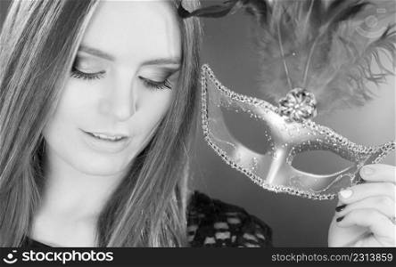 Party time, holidays, people and celebration concept. Woman long hair holding carnival mask close up. Black & white photo. Woman holding carnival mask closeup