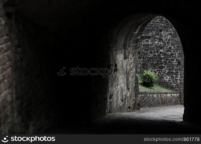 Passage through dark gate with stone wall