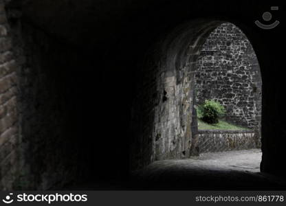 Passage through dark gate with stone wall