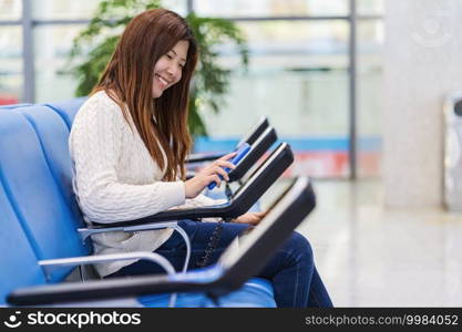 passenger holding and scanning mobile phone with qr code scanner machine of message chair in airport, Technology with travel and tourist, check-in self service,transportation concept,
