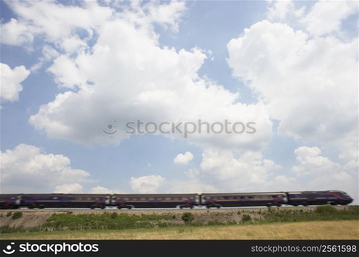 Passenger Train Moving Beneath A Clouded Sky