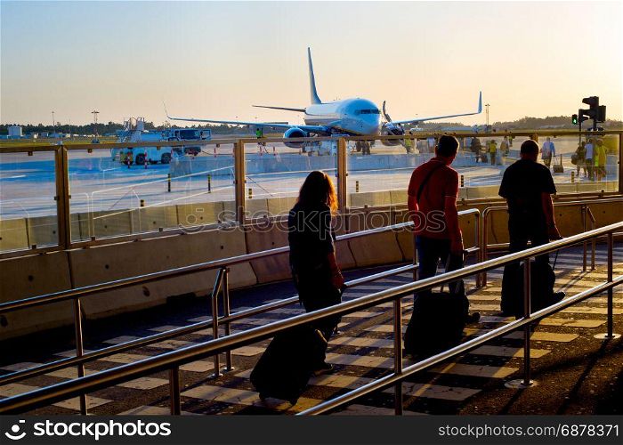 Passengers boarding airplane at an airport at sunset