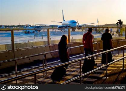 Passengers boarding airplane at an airport at sunset
