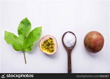 Passion fruit and leave with salt in wooden spoon on wooden white background.