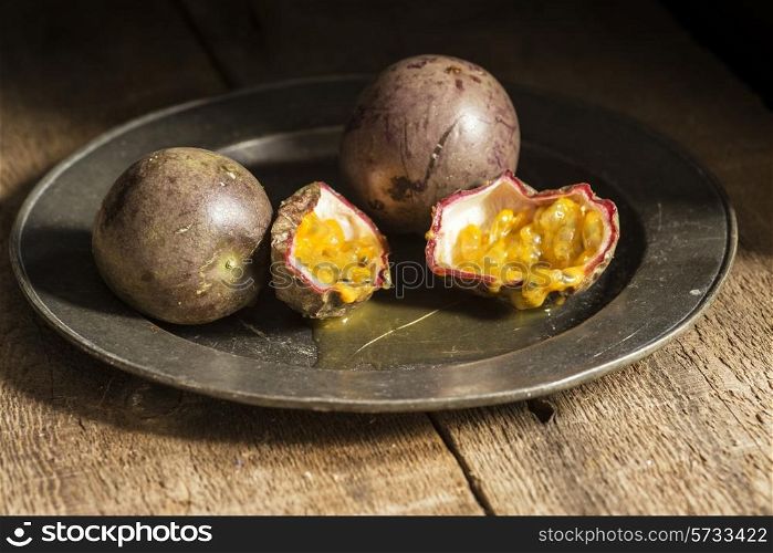 Passion fruit in moody natural light setting with vintage style. food, fresh, raw, fruit, vegetables, wood, wooden, background, grunge, retro, vintage, moody, dark,