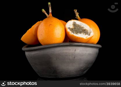 Passion fruit maracuja granadilla on ceramic black bowl, black background.