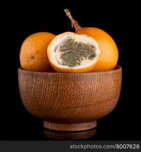 Passion fruit maracuja granadilla on wooden bowl, black background.
