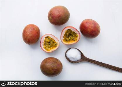 Passion fruit with salt in wooden spoon on wooden white background.