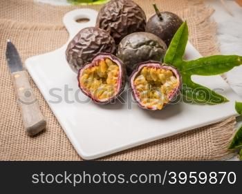 Passion fruits on white ceramic tray on wooden table background.