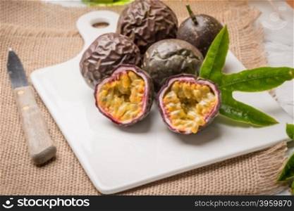 Passion fruits on white ceramic tray on wooden table background.
