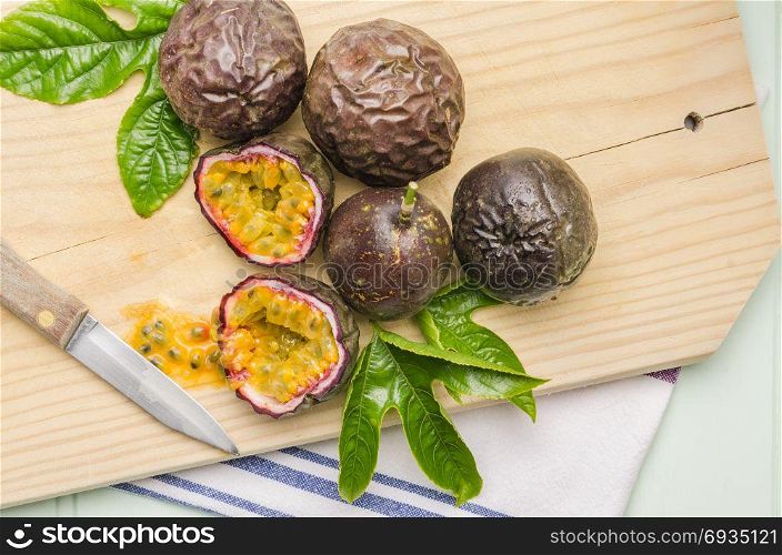 Passion fruits with leaves and knife on the vintage wooden table.