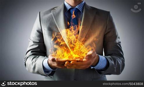 Passionate for power. Businessman hands holding fire flames in palms