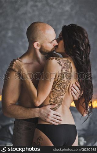 Passionate kiss of a man and a girl with a tattoo.. The pattern of the mehendi on your naked back girls 215.