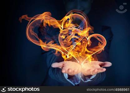 Passionate love hearts. Glowing love hearts symbols in palms on dark background