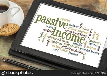 passive income word cloud on a digital tablet with a cup of coffee