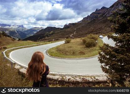 Passo Pordoi. girl looks at the turn of the road in the mountains Dolomites, Italy