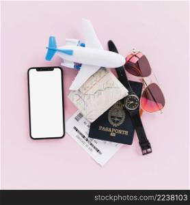 passport map tickets toy airplane wrist watch mobile phone sunglasses pink background