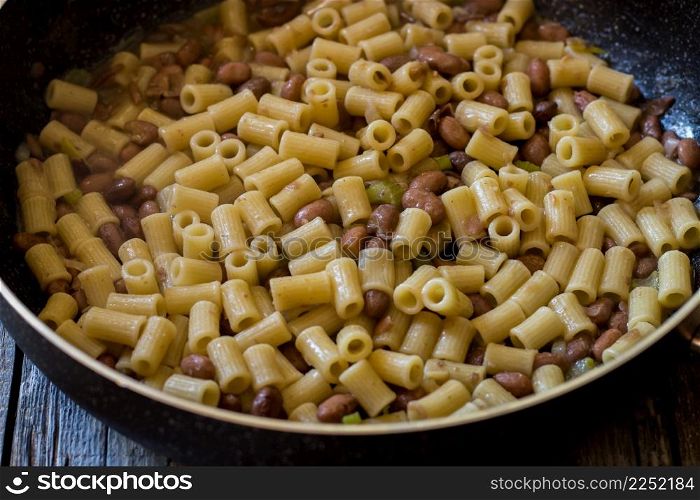 pasta and beans in a pan with celery and onion