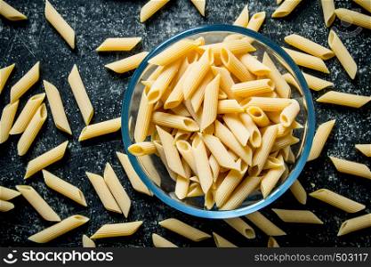 Pasta background. Dry pasta in a bowl. On black rustic background. Pasta background. Dry pasta in a bowl.