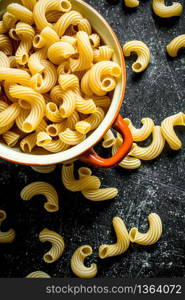 Pasta background. Dry the pasta in the pan. On black rustic background. Pasta background. Dry the pasta in the pan.