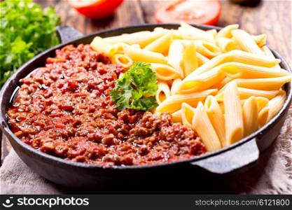 pasta bolognese in a pan on wooden table