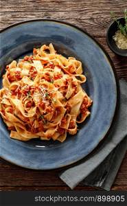 Pasta bolognese. Traditional italian dish of pasta with tomato and meat mince sauce served in a plate with parmesan cheese and thyme, top view
