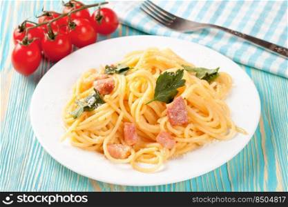 Pasta Carbonara with ham and parmesan cheese served on a white plate on blue wooden table. Top view, flat lay. Pasta Carbonara served on a white plate.