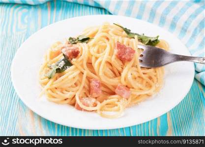 Pasta Carbonara with ham and parmesan cheese served on a white plate on blue wooden table. Top view, flat lay. Pasta Carbonara served on a white plate.