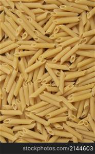 pasta concept hundreds of hollow cylinder-shaped penne pasta with slanted edges being lay in full area.