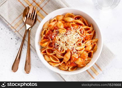 Pasta conchiglie with tomato sauce and parmesan cheese in white dish, simple meal concept