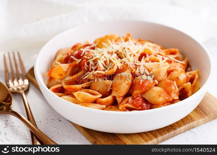 Pasta conchiglie with tomato sauce and parmesan cheese in white dish, simple meal concept