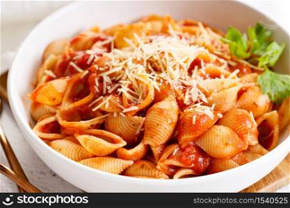Pasta conchiglie with tomato sauce and parmesan cheese in white dish, simple meal concept