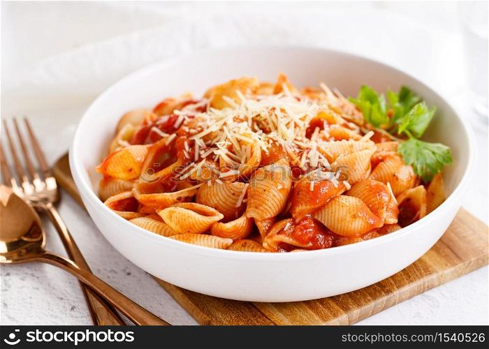 Pasta conchiglie with tomato sauce and parmesan cheese in white dish, simple meal concept