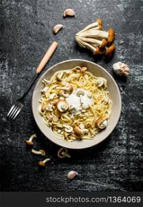 Pasta in bowl with mushrooms and garlic. On black rustic background. Pasta in bowl with mushrooms and garlic.