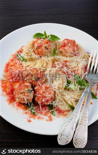 Pasta in tomato gravy with meatballs sprinkled Parmesan and basil