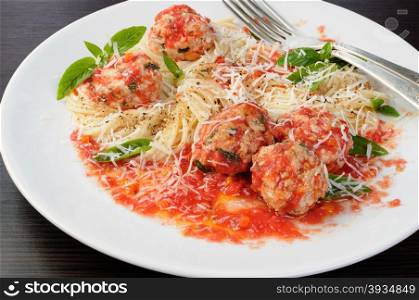 Pasta in tomato gravy with meatballs sprinkled Parmesan and basil