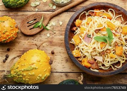 Pasta or spaghetti with pumpkin and bacon.Pasta carbonara on wooden table.Seasonal autumn food. Autumn pasta with pumpkin and bacon