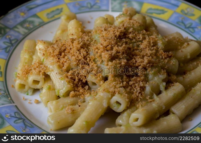 Pasta rigata with organic romanesco broccoli sauce and sprinkled with toasted breadcrumbs on black wooden background