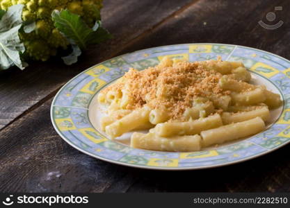 Pasta rigata with organic romanesco broccoli sauce and sprinkled with toasted breadcrumbs on black wooden background