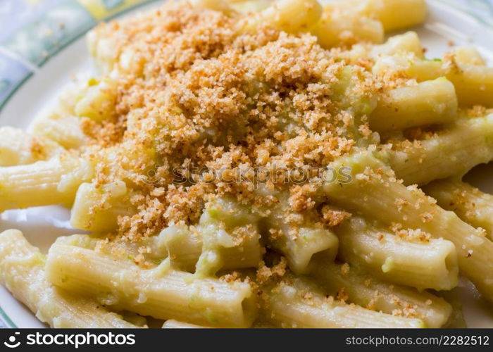 Pasta rigata with organic romanesco broccoli sauce and sprinkled with toasted breadcrumbs on black wooden background