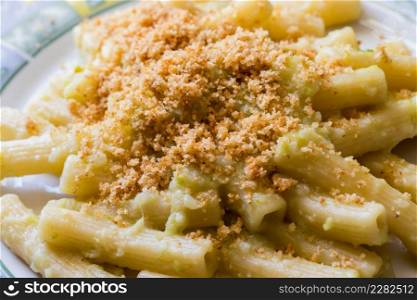 Pasta rigata with organic romanesco broccoli sauce and sprinkled with toasted breadcrumbs on black wooden background