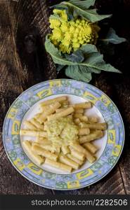 Pasta rigata with organic romanesco broccoli sauce on black wooden background