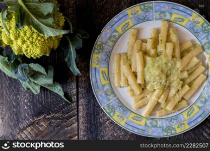 Pasta rigata with organic romanesco broccoli sauce on black wooden background