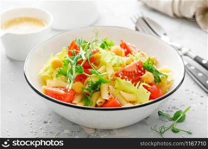 Pasta salad with fresh tomato, chickpea, lettuce and pea sprouts in lunch bowl