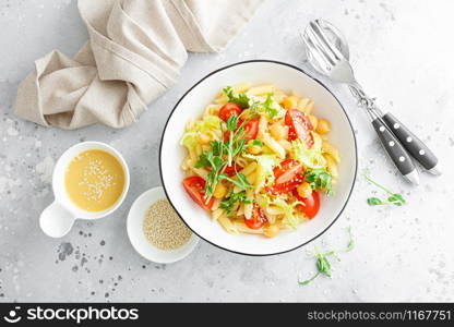 Pasta salad with fresh tomato, chickpea, lettuce and pea sprouts in lunch bowl