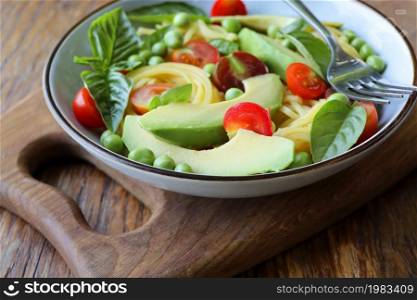Pasta salad with green peas, avocado, cherry tomatoes and basil on rustic wooden background. Top view.. Pasta salad with green peas, avocado, cherry tomatoes and basil on rustic wooden background. Top view