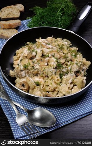Pasta sauce with mushrooms in a pan on the table with bread and dill